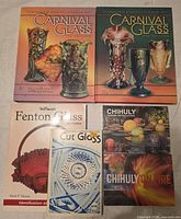 All six items laid out: two Carnival Glass encyclopedias, Warman’s Fenton Glass, Cut Glass guide, two Chihuly postcard sets