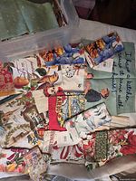 Assorted folded towels spread on table with bin showing variety of prints and some tags