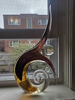 Full view of blown glass sculpture, showing spiral base, amber lower section, clear mid-section with orb, purple upper curve