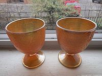 Two marigold carnival glass crackle goblets on windowsill, full view