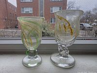 Front view of both goblets showing height difference, swirl patterns, green accents, twist stems