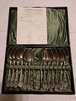 Complete set of 12 teaspoons, 1 serving spoon in fitted green satin case with paper receipt