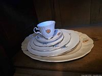 Stacked platter and plates with teacup and saucer showing floral pattern and gold trim