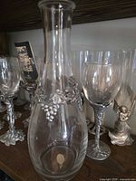 Front view decanter with grapevine collar, surrounding pewter-stem glasses visible