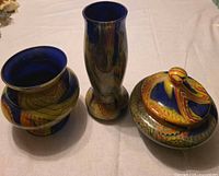 Three hand-blown glass pieces: two vases and one covered jar displayed together