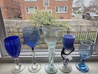 Front view of five blue art glass goblets on windowsill