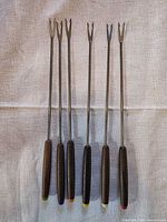 Six fondue forks laid out full length showing handles and colour-coded ends