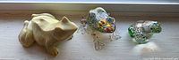 All three frog paperweights side by side on windowsill