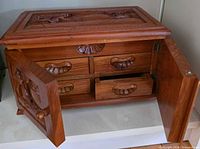 Front view showing carved lid, two open doors and four drawers