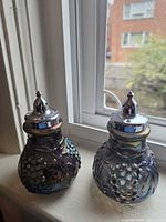 Pair of carnival glass shakers front view on windowsill