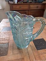 Front view of aqua iridescent hobstar pressed glass pitcher