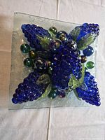 Top view of entire glass centerpiece showing grape clusters, marbles and square plate