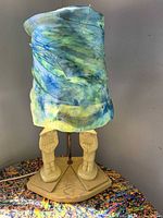 Full lamp front view showing ceramic base, metal pole, shade with blue-green scarf