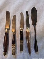 Five knives laid out showing handles and blades
