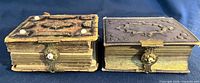 Two small 19th-century leather photo albums side by side showing embossed covers, brass clasps, gilt page edges, and wear