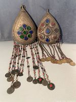 Front view of both fibulae showing cabochons, engraving, chains and coins