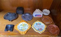 All 10 assorted vintage ashtrays on shelf