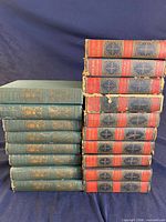 Stacked view of 8 green Poe volumes and 10 blue/red-spine Dickens volumes showing bindings and wear