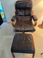 Front view of Westnofa armchair with ottoman showing leather wear and wooden frame