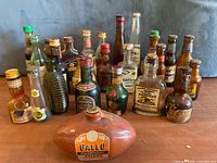 Group of approximately 25 empty vintage miniature liquor, beer and soda bottles with a football-shaped Gallo Sherry bottle in front