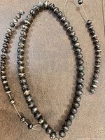 Full necklace and partial strand displayed on flat surface