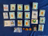 Overall view of approximately 20 pins laid out on blue fabric, showing Irish crest pins on cards and U.S. travel pins