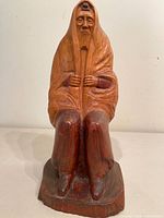 Full view of carved wood statue showing seated bearded man with tefillin and shawl