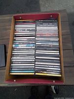 Cardboard box filled with two rows of CDs showing spines