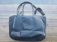 Front view showing nylon body, leather handles, shoulder strap, front zip pockets