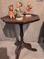 Wood accent table with four Hummel figurines displayed