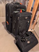 Three black American Tourister luggage pieces standing to show overall design and condition