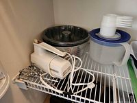 Hand mixer, stainless angel food pan, bundt pan, Tupperware bowl, measuring cups stacked