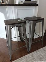 Front angled view of both matching metal bar stools under counter