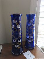 Both cobalt blue floral vases on tabletop