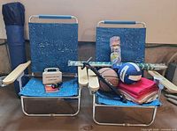 Overall lot showing two chairs, tent bag, umbrella, balls, pump, towels, cups, first aid kit and flashlight