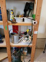 Full shelving view with watering can, gloves, hose fittings, soil bags