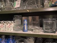 Shelf view showing ceramic bag vases, ribbed glass vase, blue jasperware-style vase, cube glass vases and flower frog