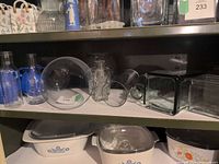 Full shelf showing assortment of glass vases, blue ceramic urns, milk bottles, and other pieces