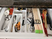 Full drawer view showing variety of utensils, skewers, steak knives, corn holders