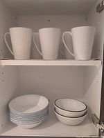 Mugs on upper shelf, bowls on lower shelf