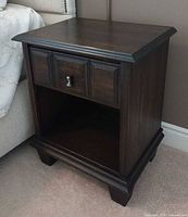 Front view of first nightstand showing drawer, open shelf and top surface