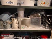 Overview of shelf with assorted planters, watering can and plant stand