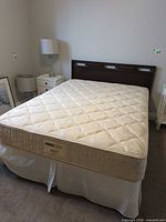 Full view of assembled queen bed with mattress, box spring, headboard, frame and skirt