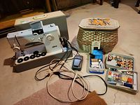 Full lot showing sewing machine, case, wicker basket, pedal, threads and notions