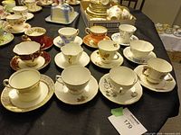 Overview of all twelve tea cup and saucer sets on table