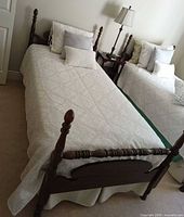 Full view of twin bed with wood headboard, footboard, bedding and pillows