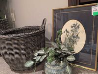 Group view of framed print, wicker basket planter, pottery planter with foliage