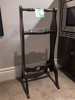 Front view of dark wood plant stand with glass dish on shelf