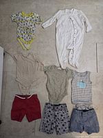 All eight baby clothing items laid out