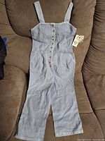 Front view of light blue chambray Billabong jumpsuit with button front and straps